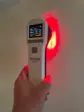 Hvid håndholdt Heat Sense Laser S 2.0 med display, der kaster rødt lys på en væg