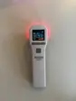 Hvid Heat Sense-laser med tændt display og rødt lys i toppen, fotograferet mod en lys væg