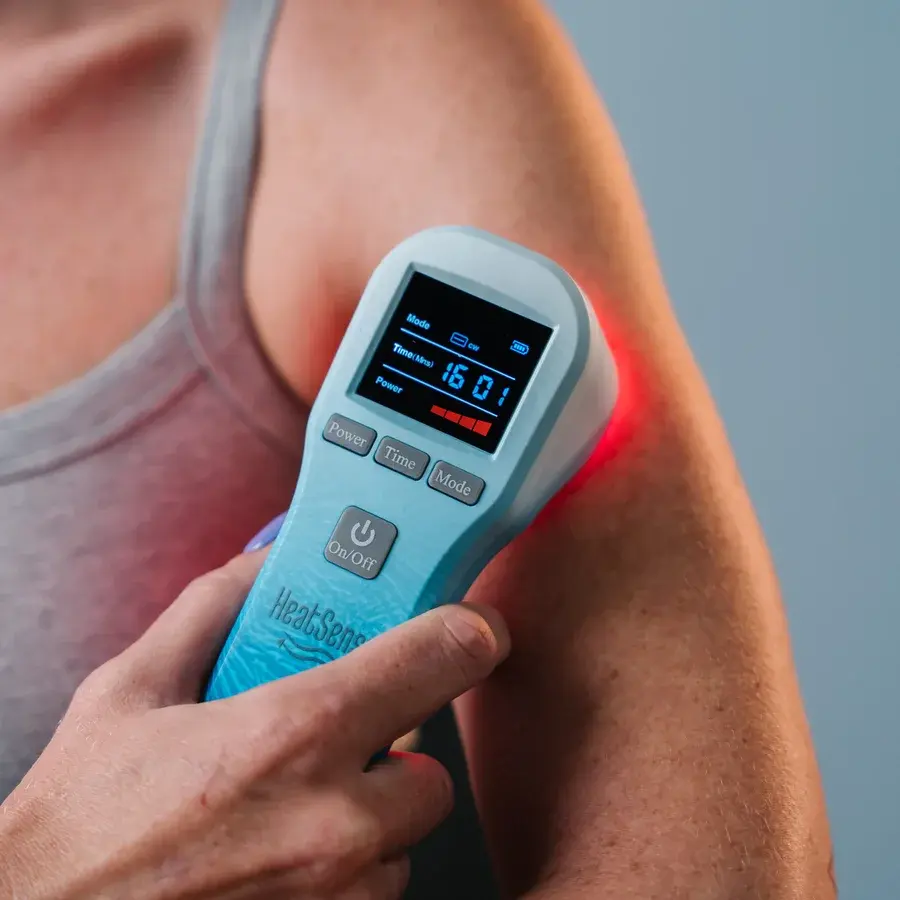 Lyseblå håndholdt laser med display og knapper til Power, Time og Mode, holdt mod en skulder